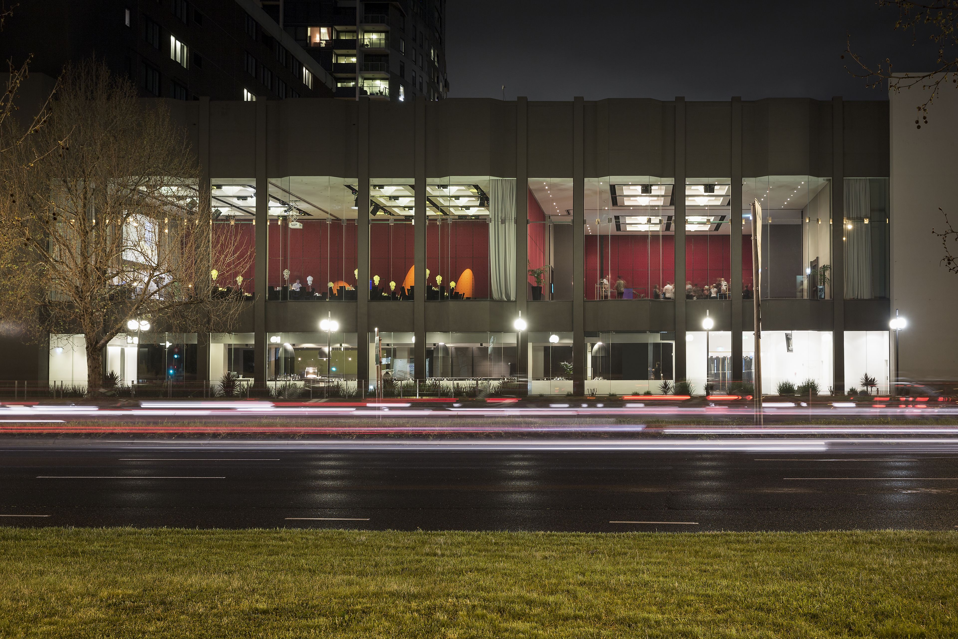 A modern building with multiple floors, large windows, and a red interior.