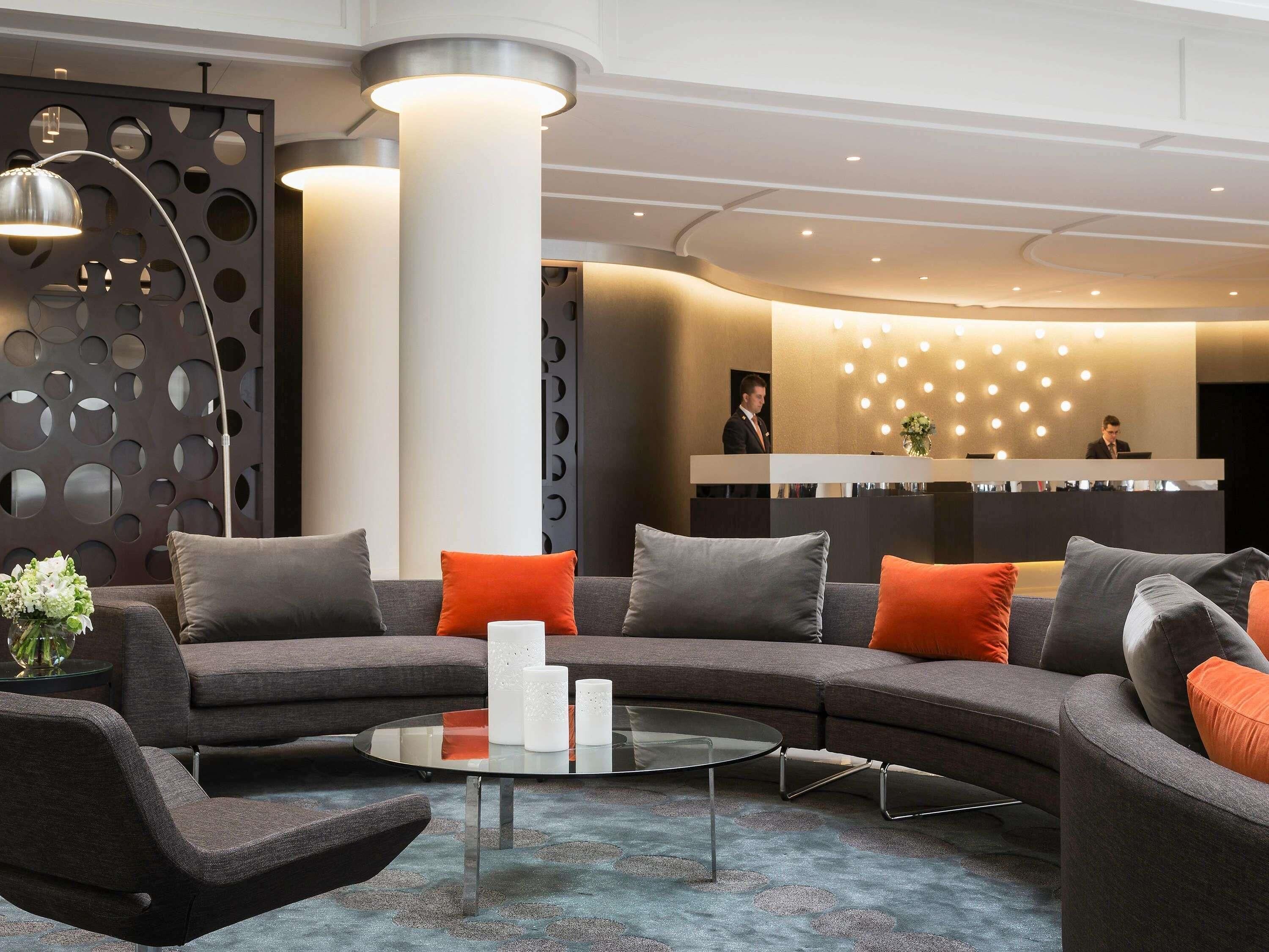 A modern lobby with a reception desk, a large sectional sofa, and a glass coffee table.