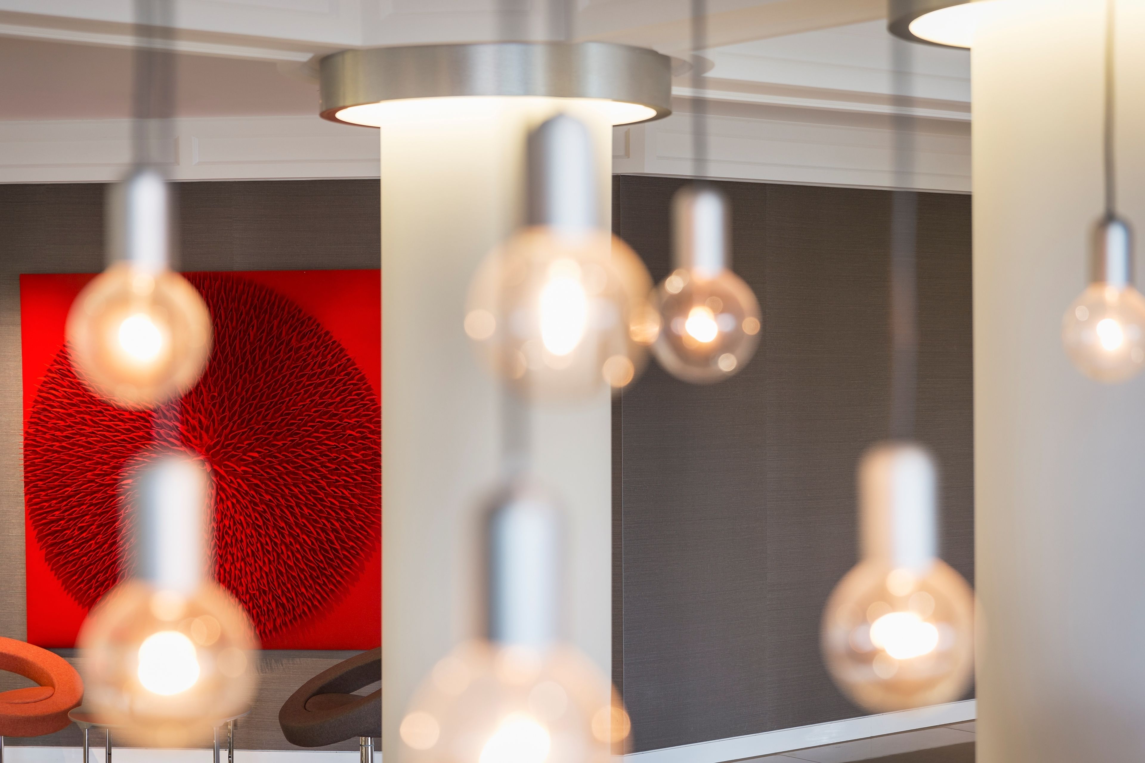 A modern interior with hanging pendant lights and a red abstract artwork on the wall.