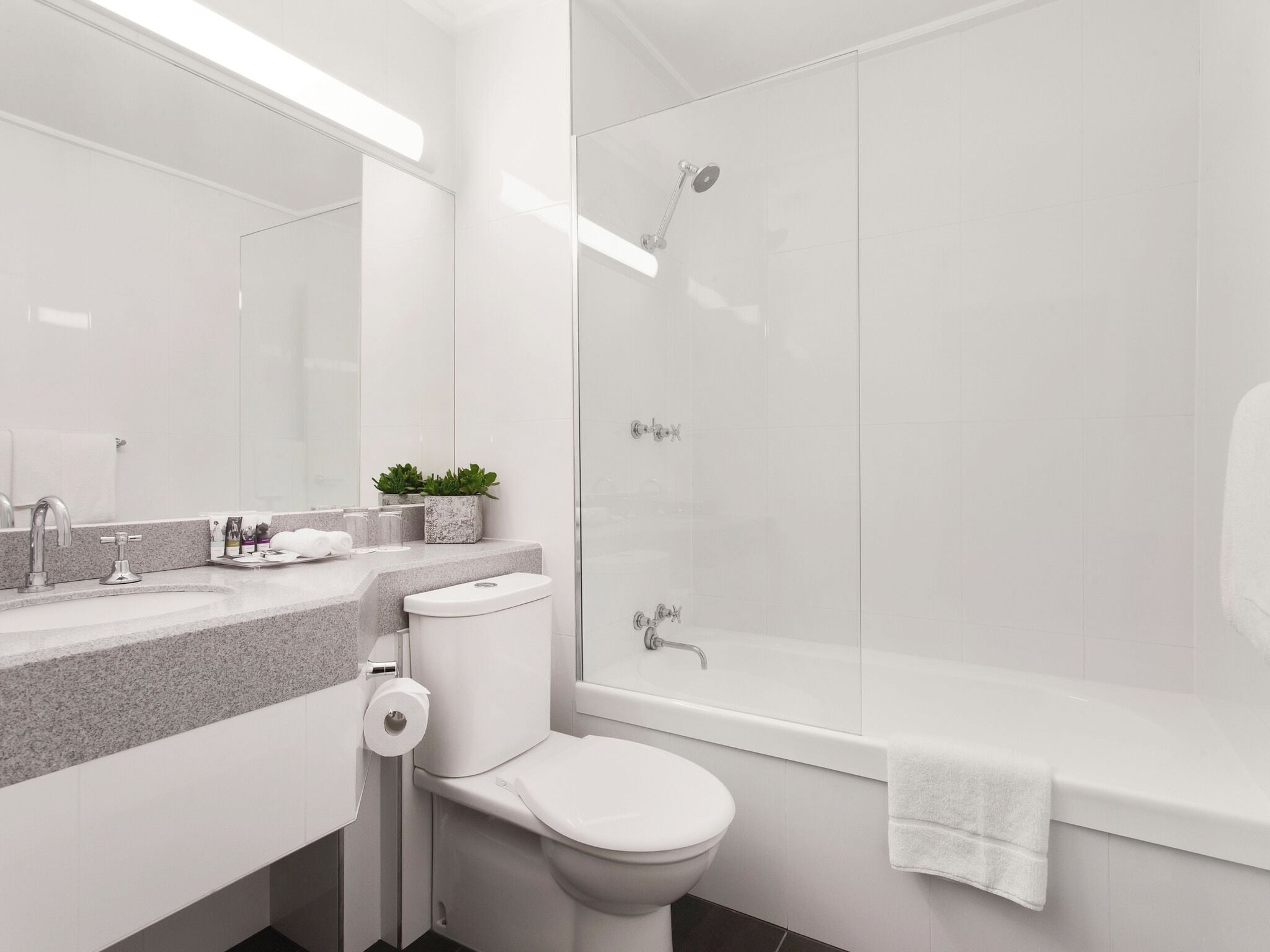 Un baño moderno con inodoro, lavamanos y ducha.