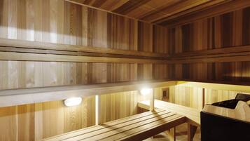 Una sauna con bancos de madera y un banco con un cubo de basura.