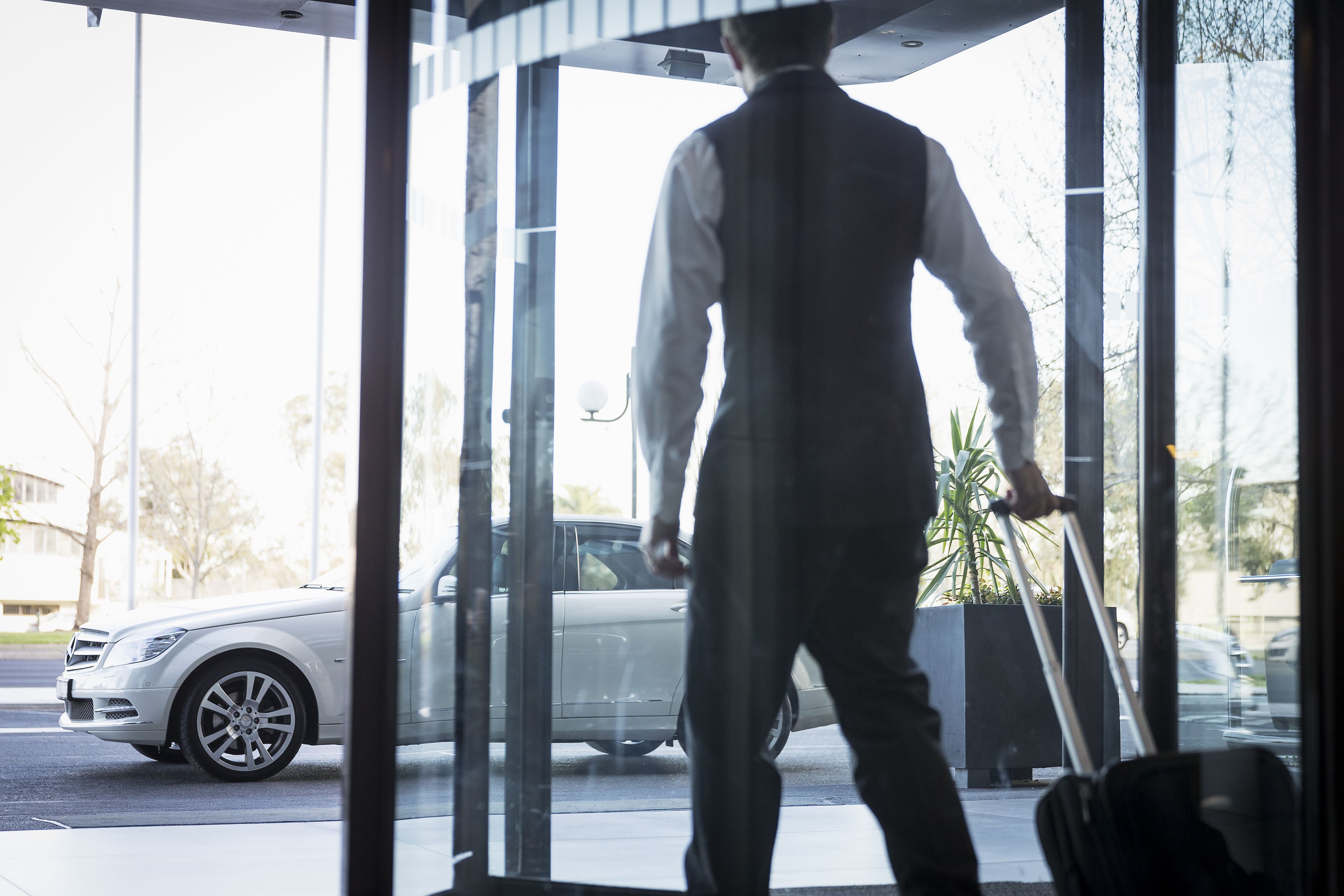 A man walking through a glass door into a building.