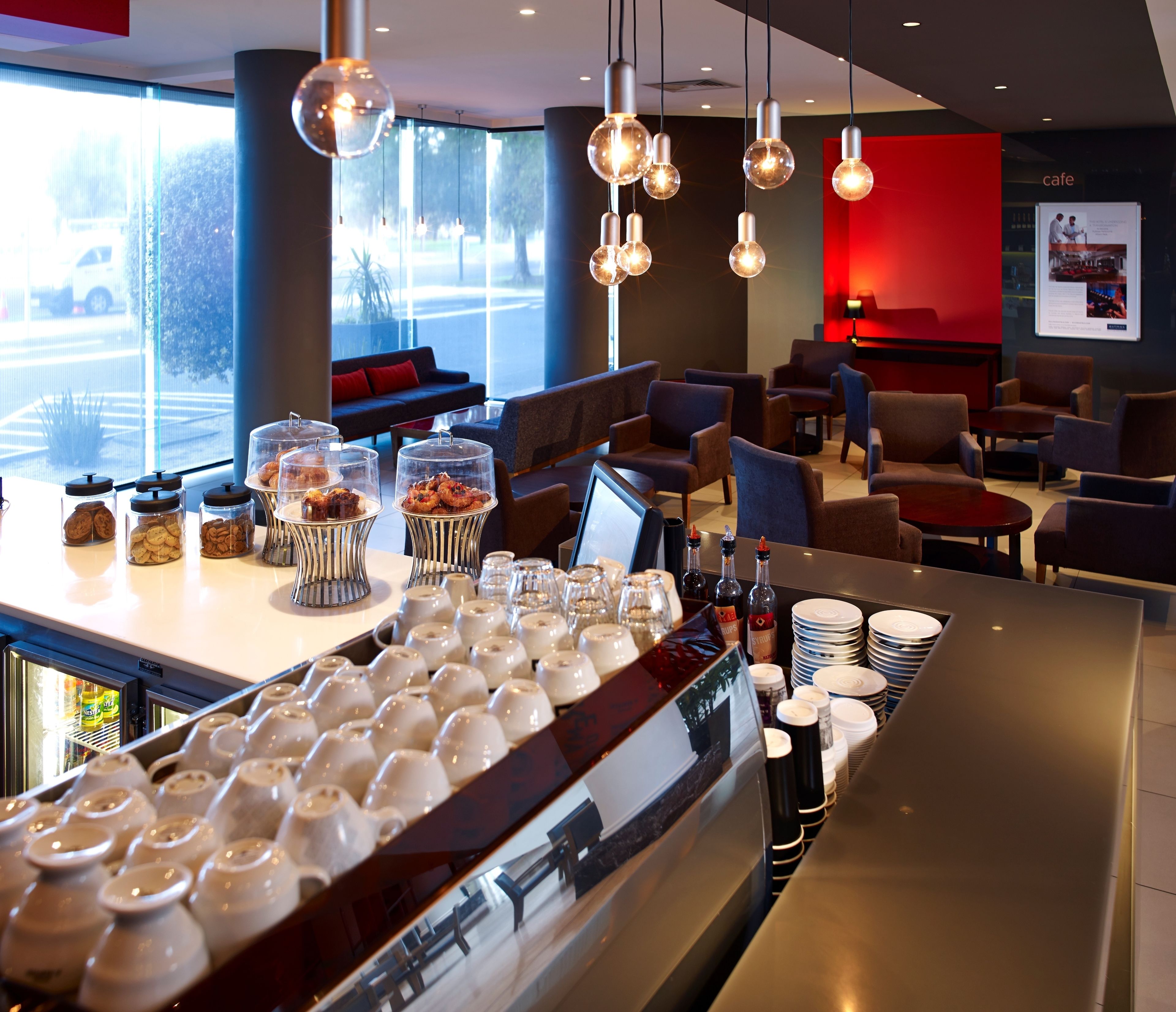A modern cafe with a bar area, seating, and a view of the street.