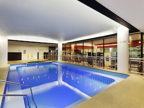 An indoor swimming pool with exercise equipment and a glass wall. - Mercure Melbourne Albert Park (Melbourne)