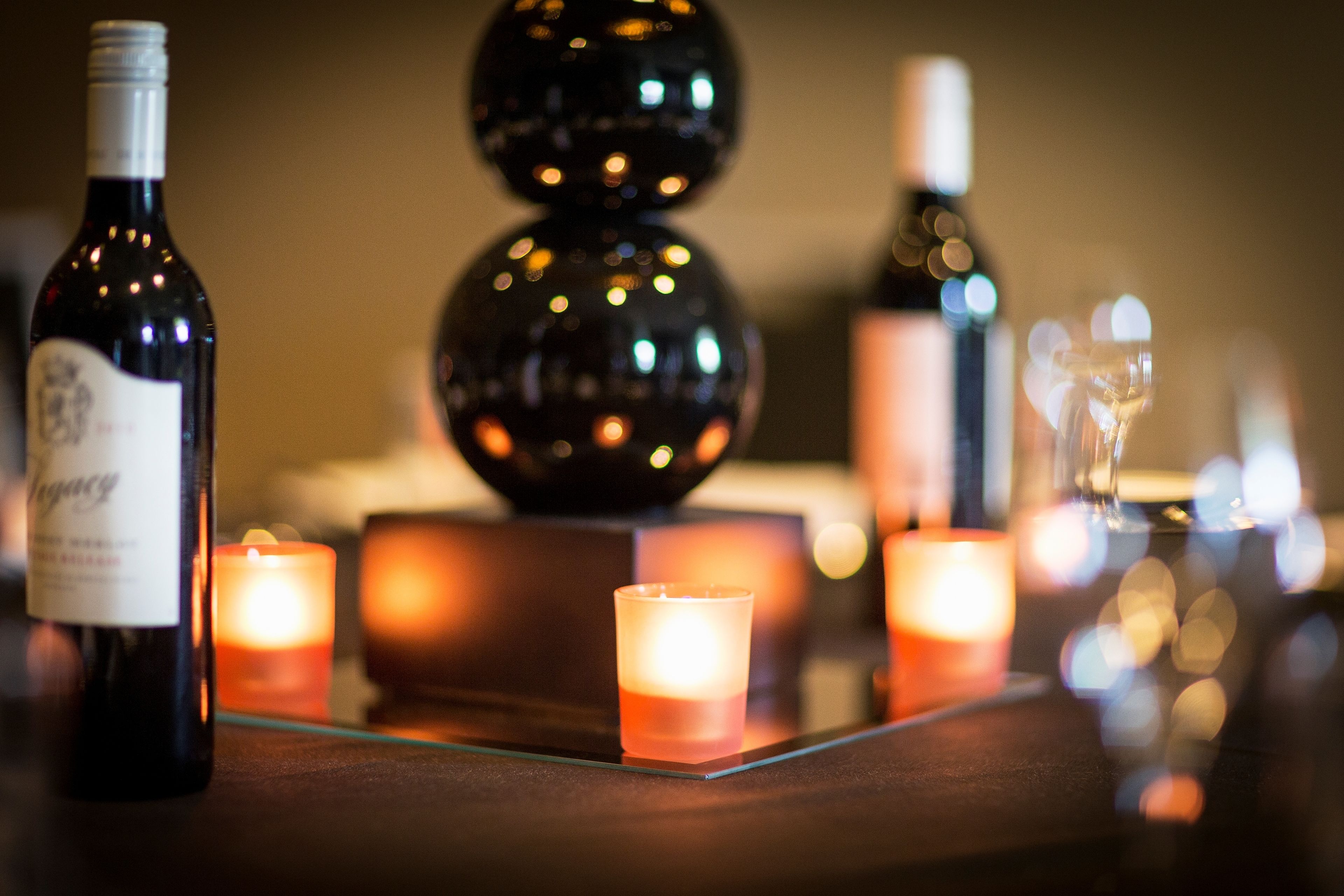 Une table avec une bouteille de vin, une bougie et un verre.