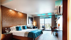 Una habitación de hotel moderna con una cama grande, un escritorio y un balcón con vistas.