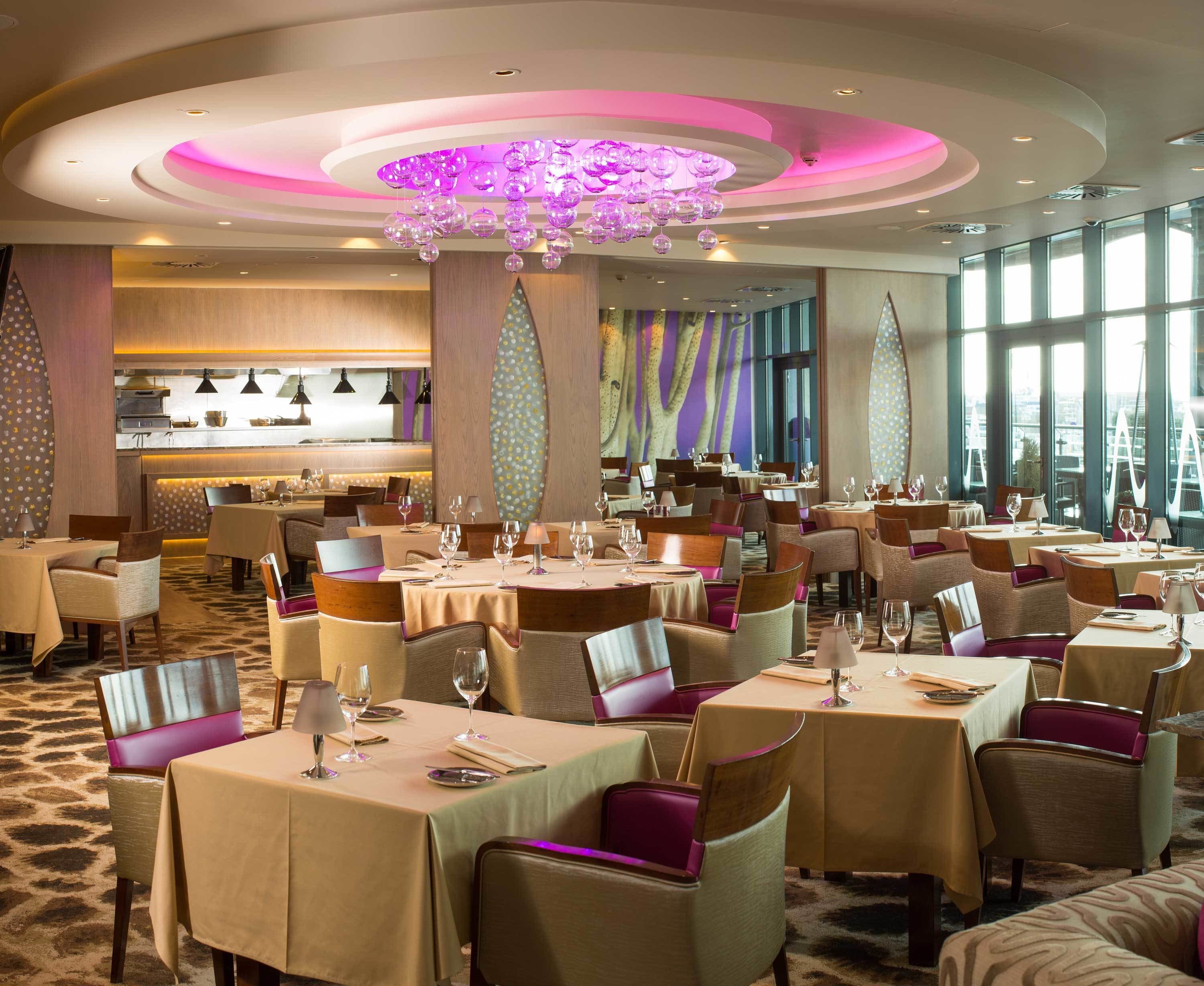 Un restaurant avec des tables rondes, des chaises et un lustre.