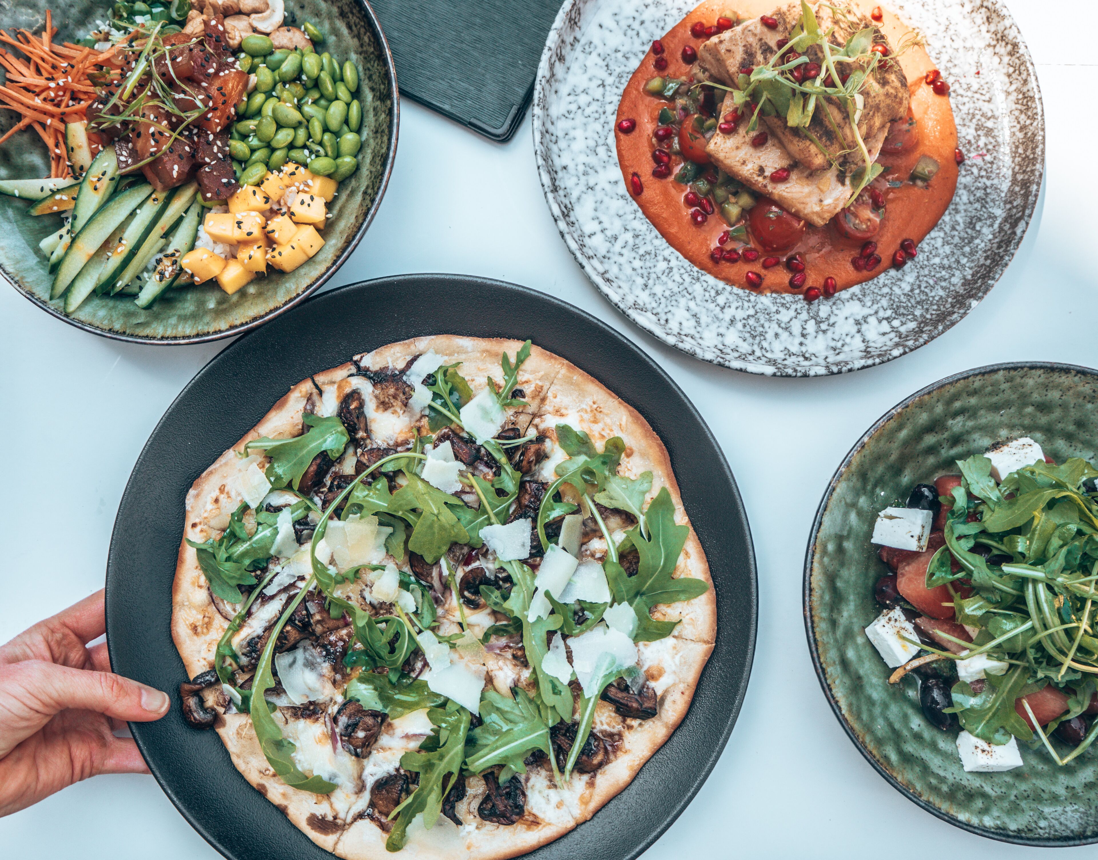 Un assortiment de plats comprenant une pizza, une salade et une soupe.