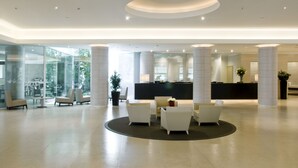 Un hall amplio con mostrador de recepción, zona de estar y ventanas grandes.