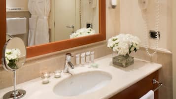 A bathroom with a sink, mirror, and a hairdryer mounted on the wall.