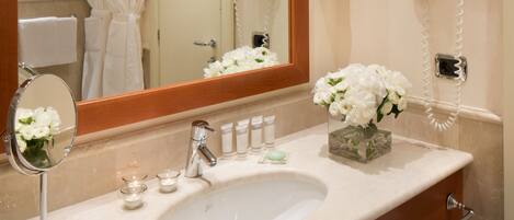 A bathroom with a sink, mirror, and a hairdryer mounted on the wall.