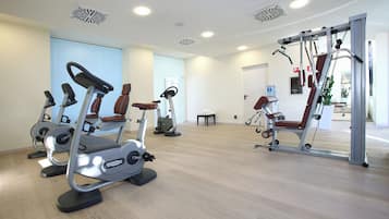 Un gimnasio con máquinas de cardio, una banca de pesas y un espejo.