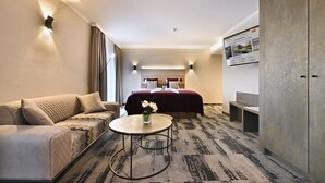 A hotel room with a bed, a sofa, a small table, and a wardrobe. - Van Der Valk Hotel Charleroi Airport (Charleroi)
