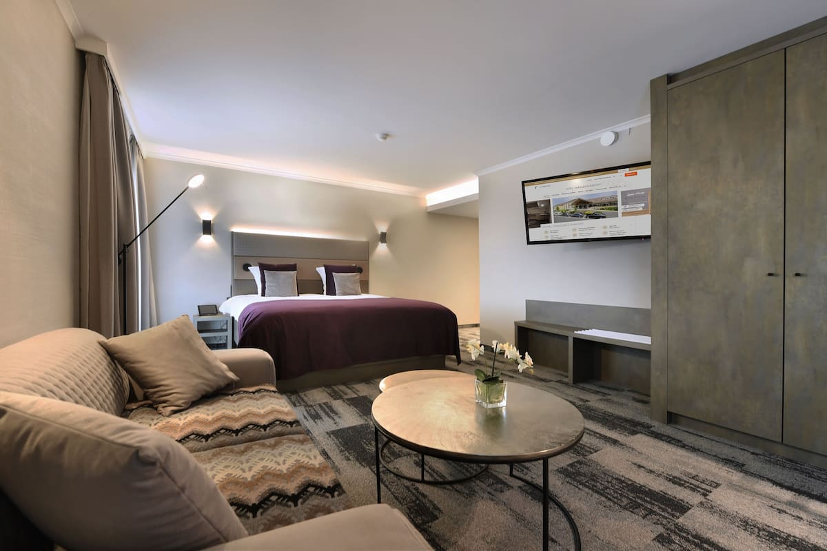 Ein modernes Hotelzimmer mit einem Bett, einer Couch und einem kleinen runden Tisch mit einer Vase.