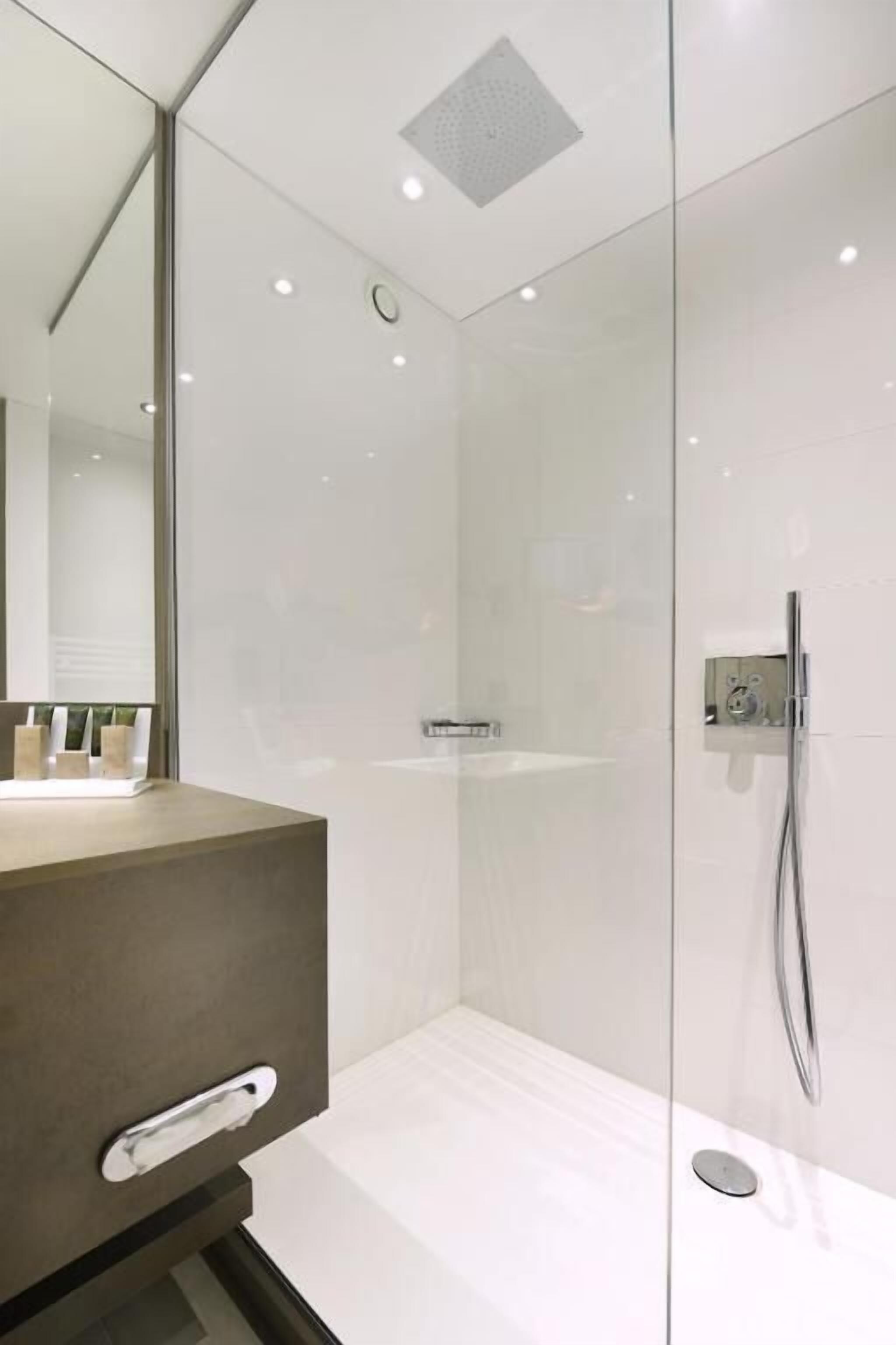 Een moderne badkamer met een douchecabine van glas, een wastafel met spiegel en een toilet.