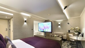 A modern hotel room with a large bed, a desk with a chair, a television, and a small table with a lamp. - Van Der Valk Hotel Charleroi Airport (Charleroi)
