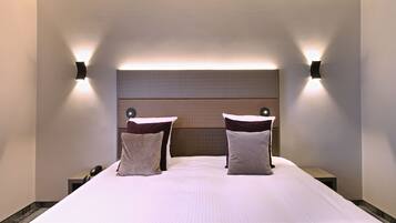 Een hotelkamer met een groot bed, twee nachtkastjes en wandlampen.