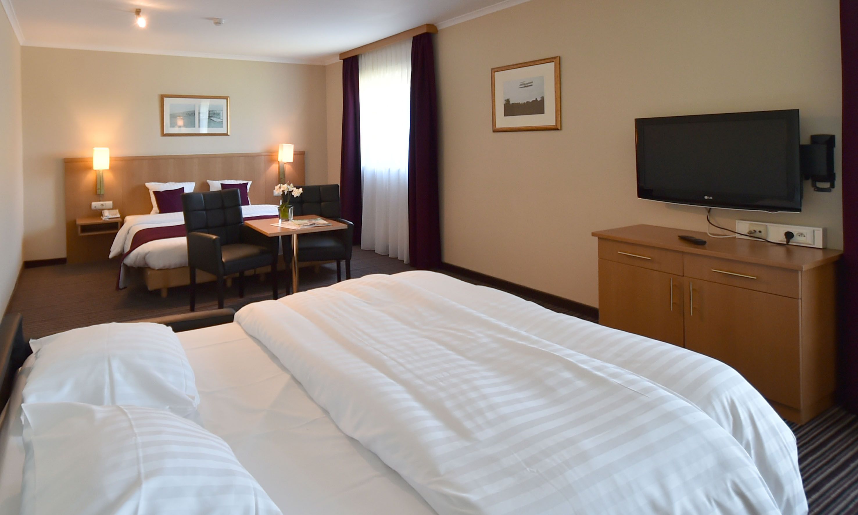 Une chambre d’hôtel avec un grand lit, un bureau avec une chaise, une télévision et une table de chevet.