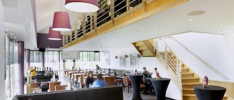 Un vestíbulo amplio con diseño moderno, que cuenta con una zona de estar grande, una escalera y un entrepiso.