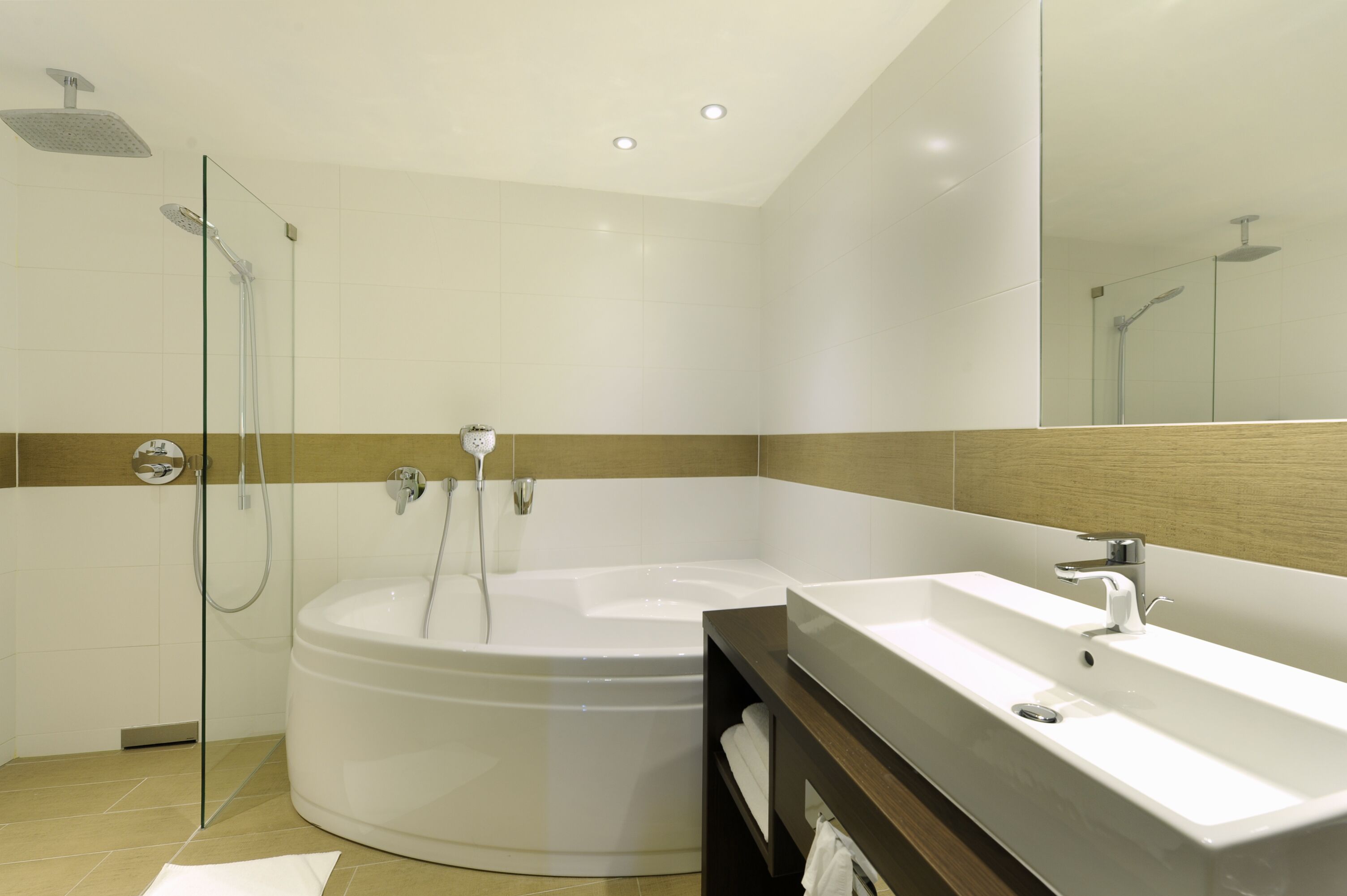 Une salle de bain moderne dotée d’une grande baignoire, d’une douche séparée et d’un meuble-lavabo.