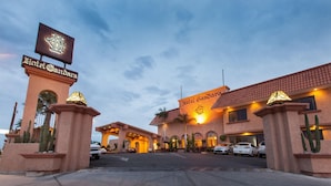 Entrada del Hotel Gandara, con un letrero llamativo, un camino de entrada pavimentado y coches aparcados.