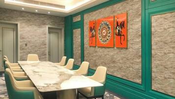 A conference room with a marble table, green chairs, and decorative wall art.