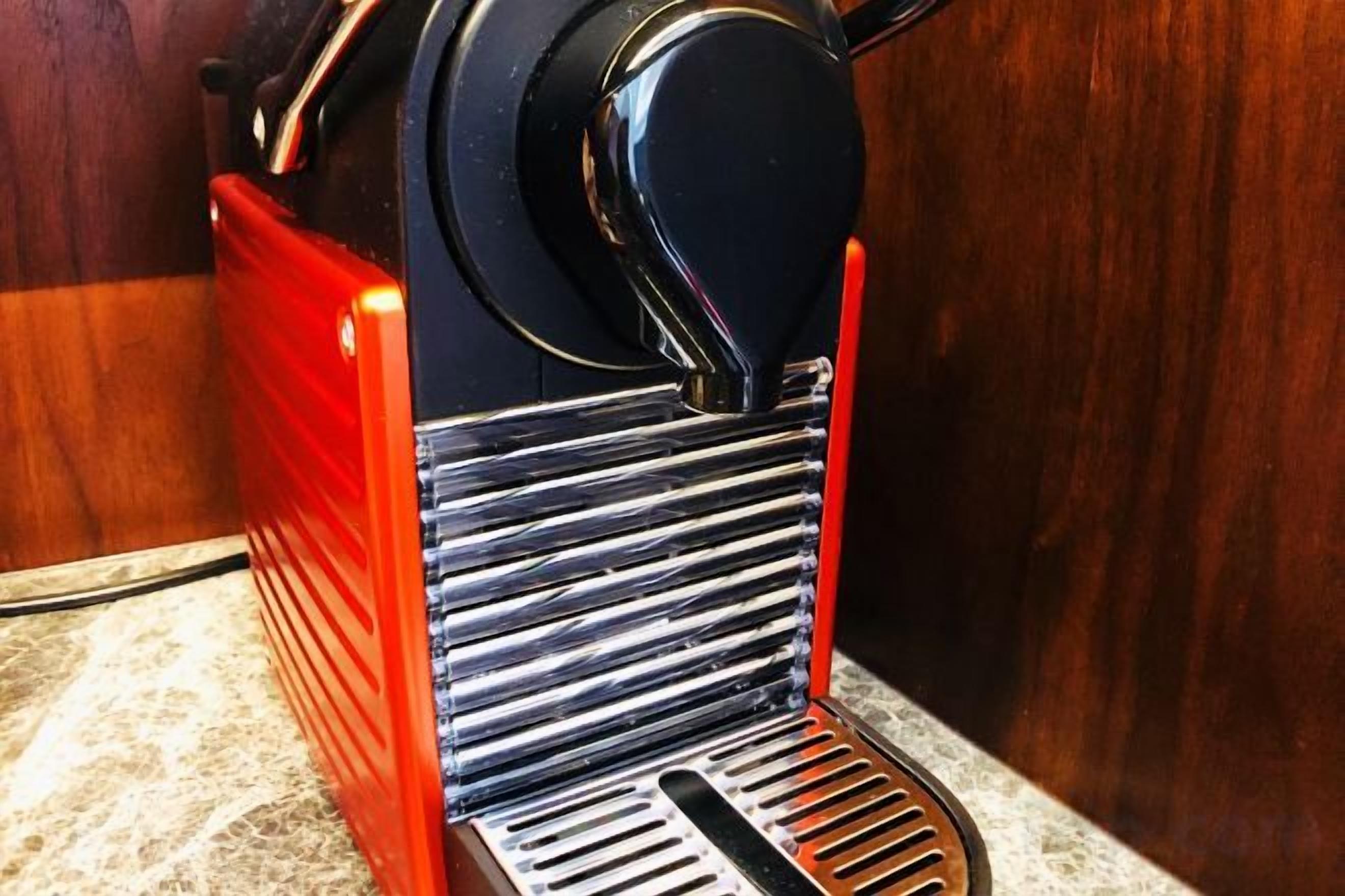 Máquina de café com design preto e vermelho, colocada sobre uma bancada.