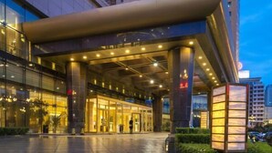 A modern hotel entrance with a covered walkway, large glass windows, and a prominent sign. - Yinlong Hotel (Xining)