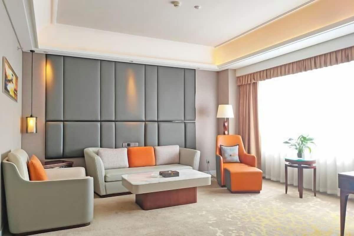 A modern hotel room with a sofa, armchair, and a small table.