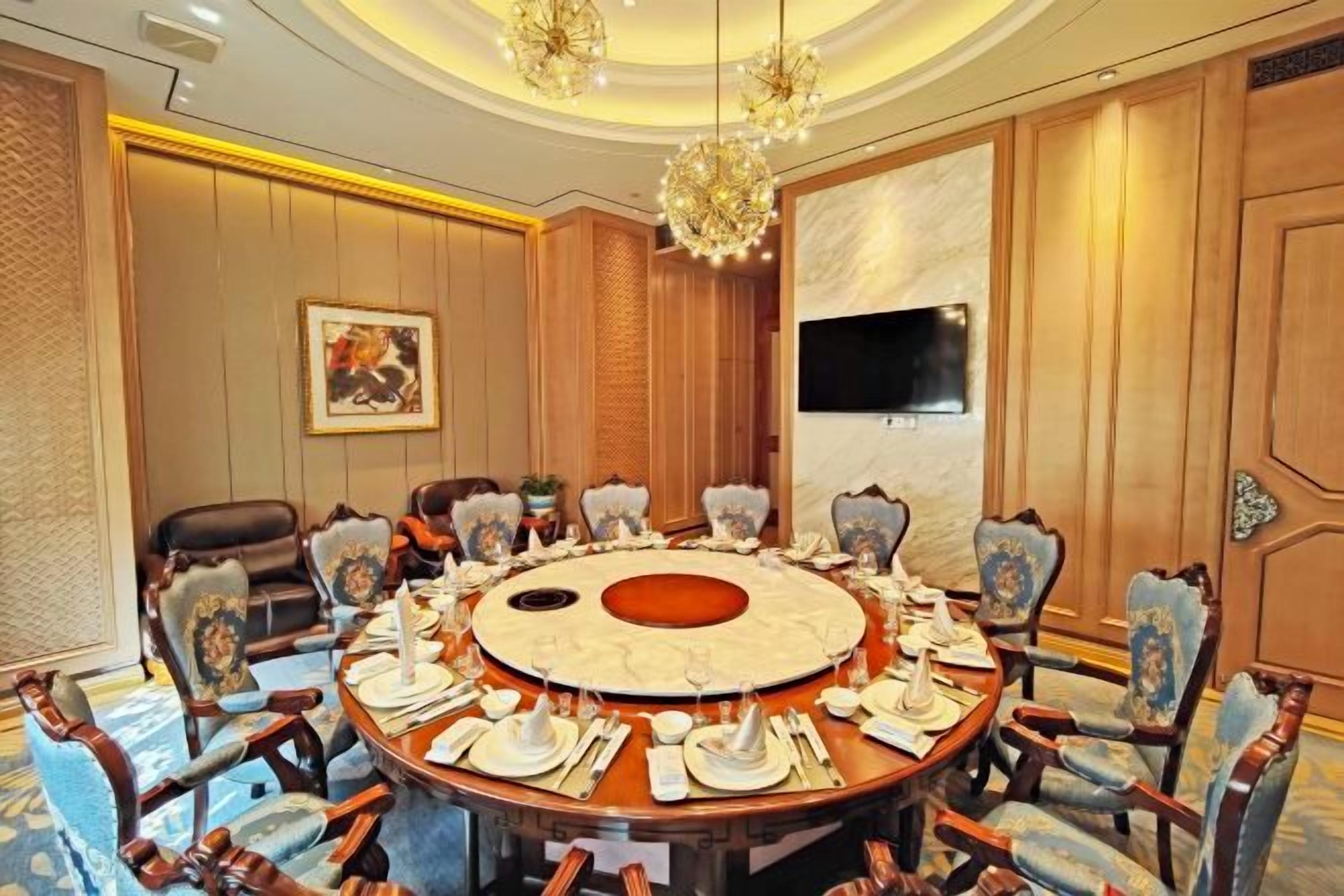 Un salón de conferencias con una mesa redonda, sillas y una araña.