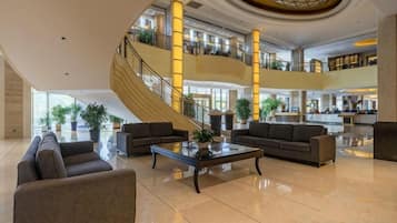 Eine geräumige Lobby mit einer zentralen Treppe, einer Sitzgelegenheit und einem Empfangsbereich.