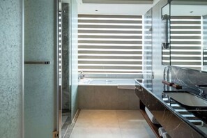 Un baño moderno con un espejo grande, una bañera y un tocador con lavamanos.