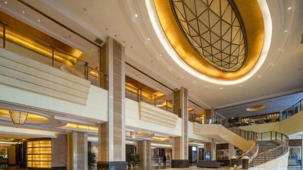 A spacious lobby with a central staircase, multiple levels, and a distinctive geometric ceiling design. - Yinlong Hotel (Xining)