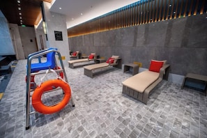 Habitación de hotel moderna con zona de masajes, una silla azul y un flotador.
