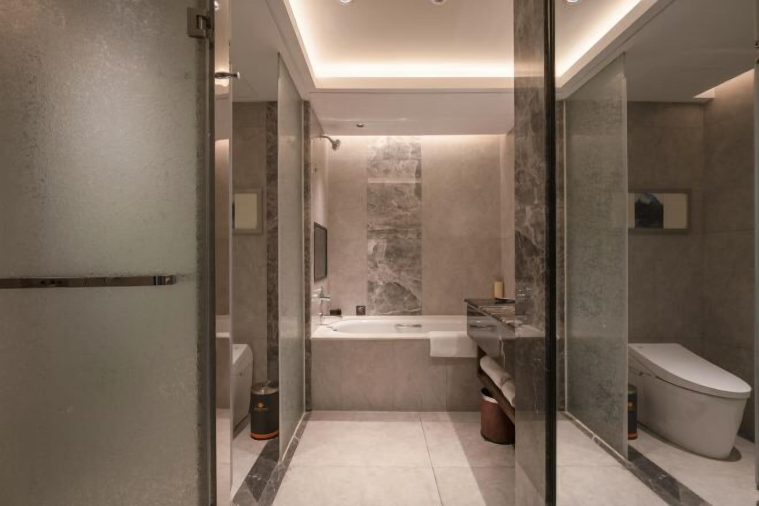A modern bathroom with a glass shower enclosure, a freestanding bathtub, and a toilet.