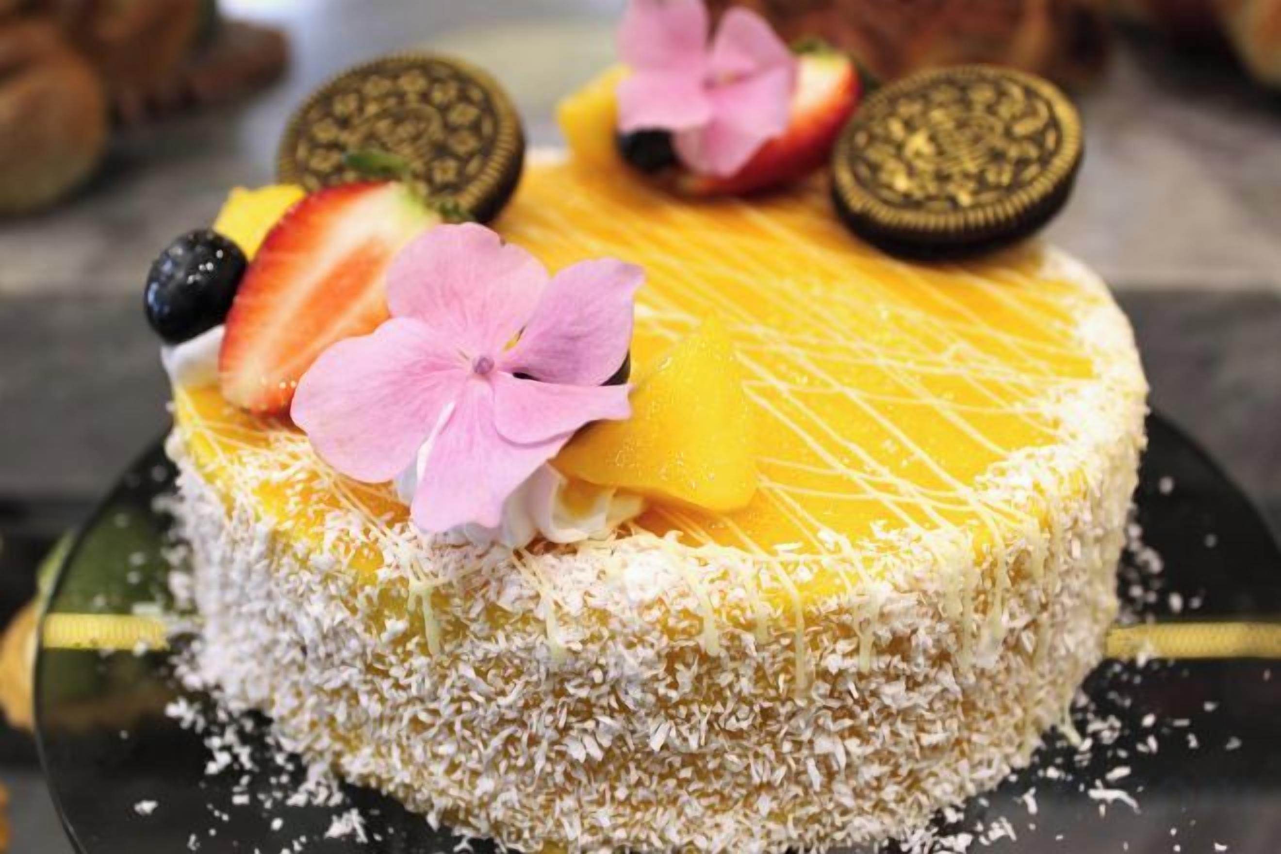 Un pastel con frutas y flores en la parte superior.