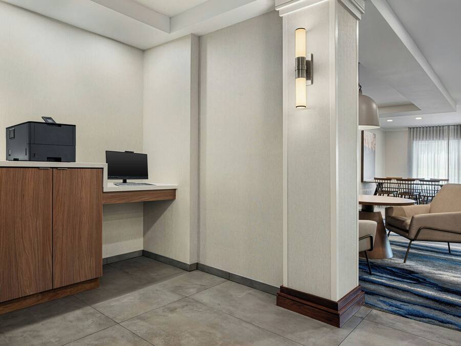 Une chambre d’hôtel équipée d’un bureau, d’un ordinateur, d’une imprimante et d’un coin salon avec des chaises et une table.