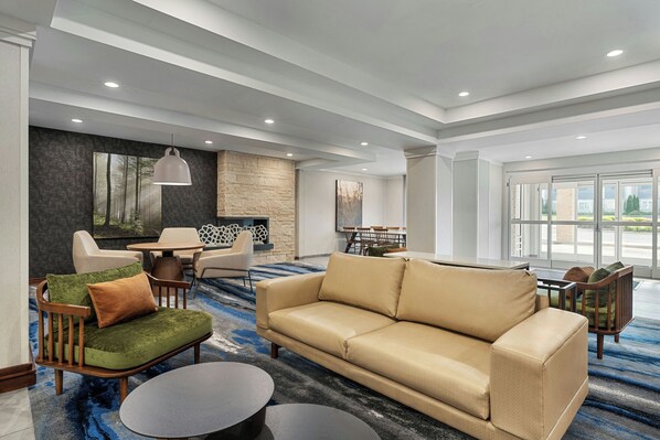 A modern lobby with a beige sofa, round tables, and a stone accent wall.