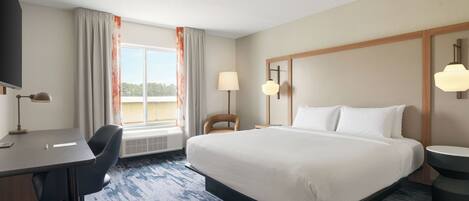 Une chambre d’hôtel équipée d’un lit, d’un bureau, d’une chaise et offrant une vue sur l’extérieur.