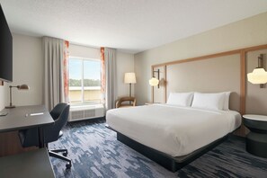 A hotel room with a bed, desk, chair, and a view of the outdoors. - Fairfield Inn & Suites by Marriott South Hill (La Crosse)