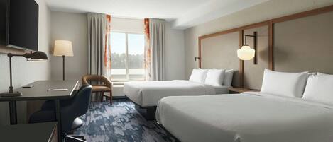 Une chambre d’hôtel équipée d’un bureau, de deux lits, d’une chaise et d’un téléviseur.