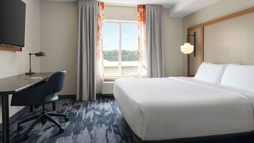 A hotel room with a bed, desk, chair, and a television.