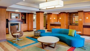 Un vestíbulo moderno de hotel con un sofá azul, una mesa de centro redonda y una chimenea.