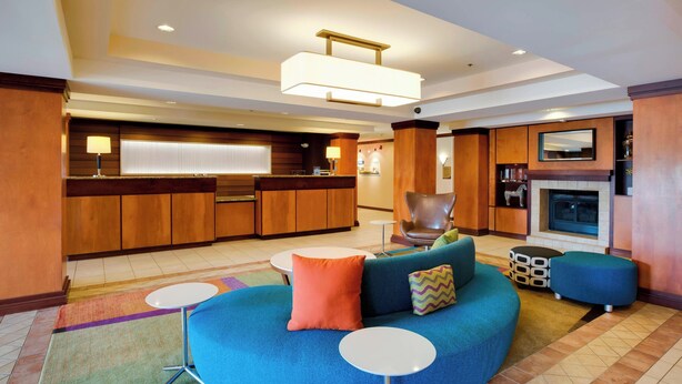 Un moderno vestíbulo de hotel con un sofá azul, una chimenea, una zona de bar y una mesa de comedor.