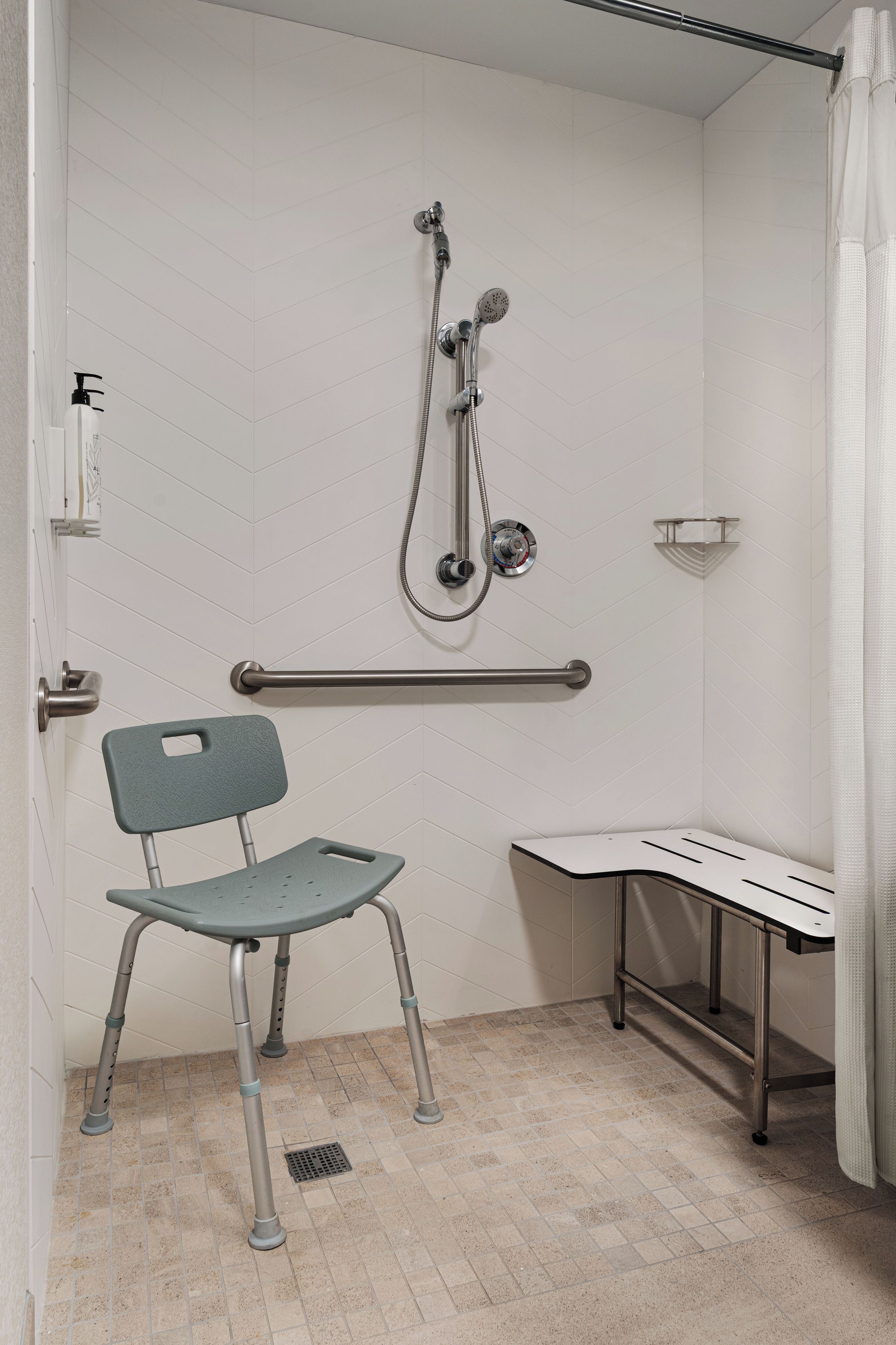 Une salle de bain équipée d’une douche, de toilettes, d’une chaise et d’un lavabo.
