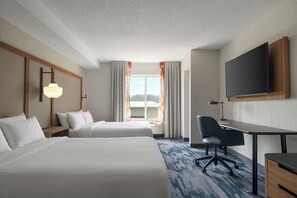 Une chambre d’hôtel avec deux lits, un bureau, une chaise, une télévision et une fenêtre avec des rideaux.