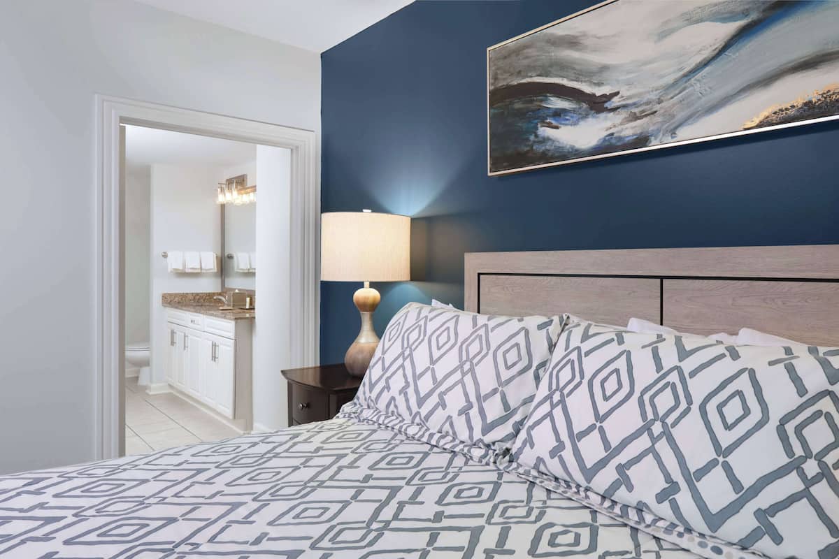 Une chambre à coucher avec un lit, une table de chevet, une lampe et un tableau au mur.