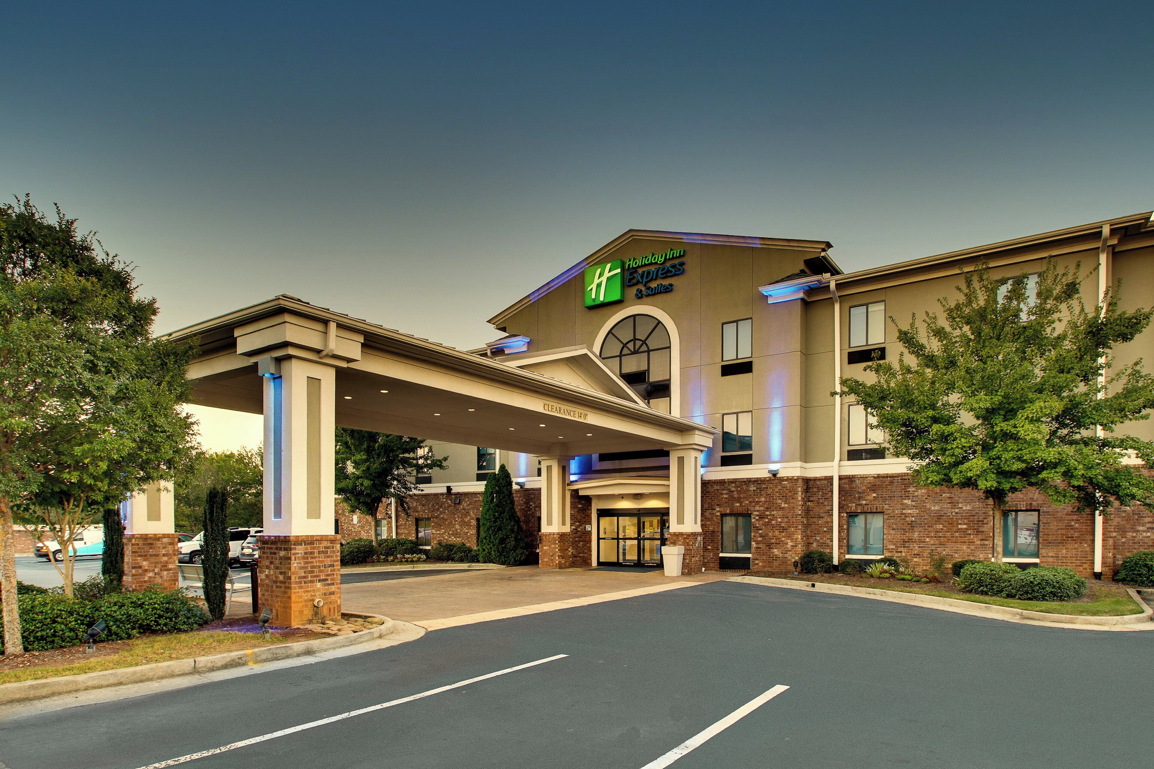 A Holiday Inn Express & Suites building with a covered entrance, brick facade, and a parking lot.