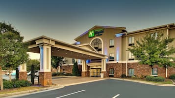 A Holiday Inn Express & Suites building with a covered entrance, brick facade, and a parking lot.