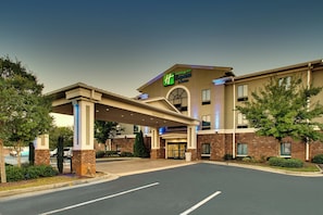 A Holiday Inn Express & Suites building with a covered entrance, brick facade, and a parking lot.